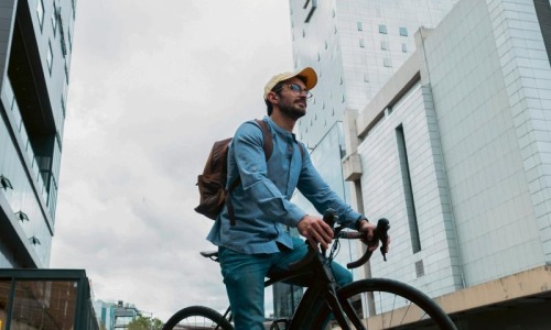 A man with a backpack riding a bicycle in the city.