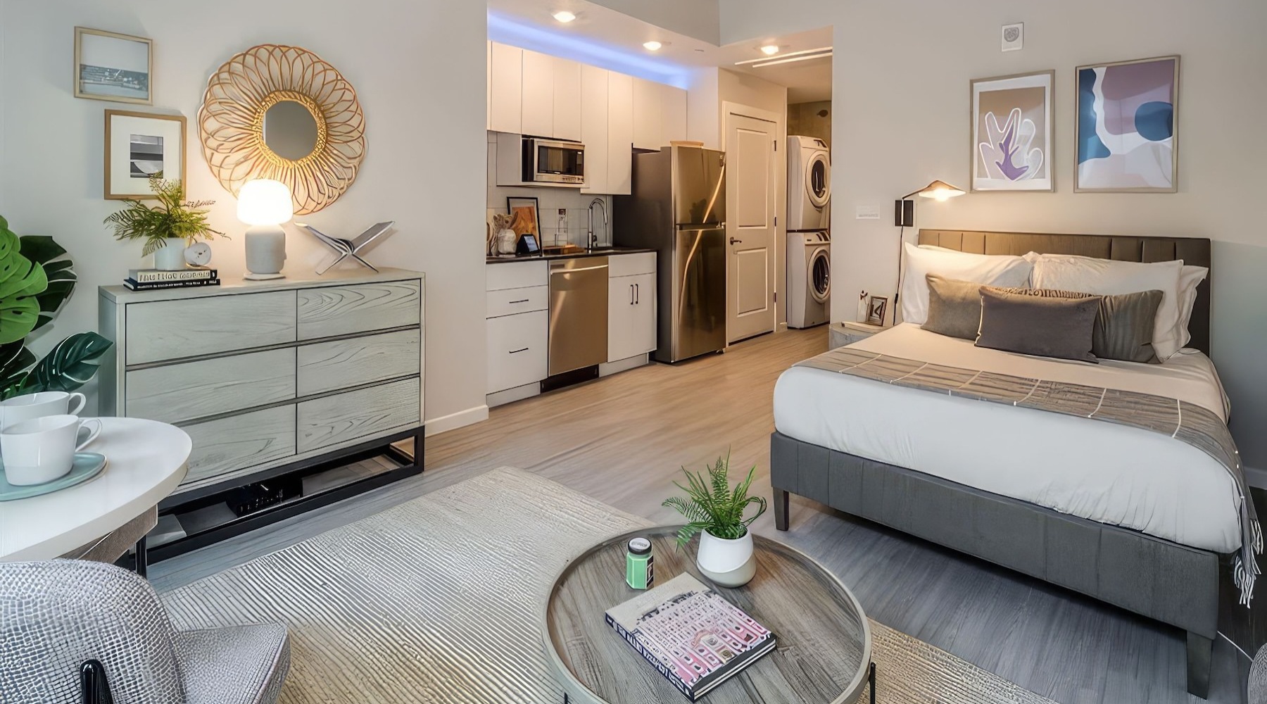 a studio with a bed, tables and a kitchen